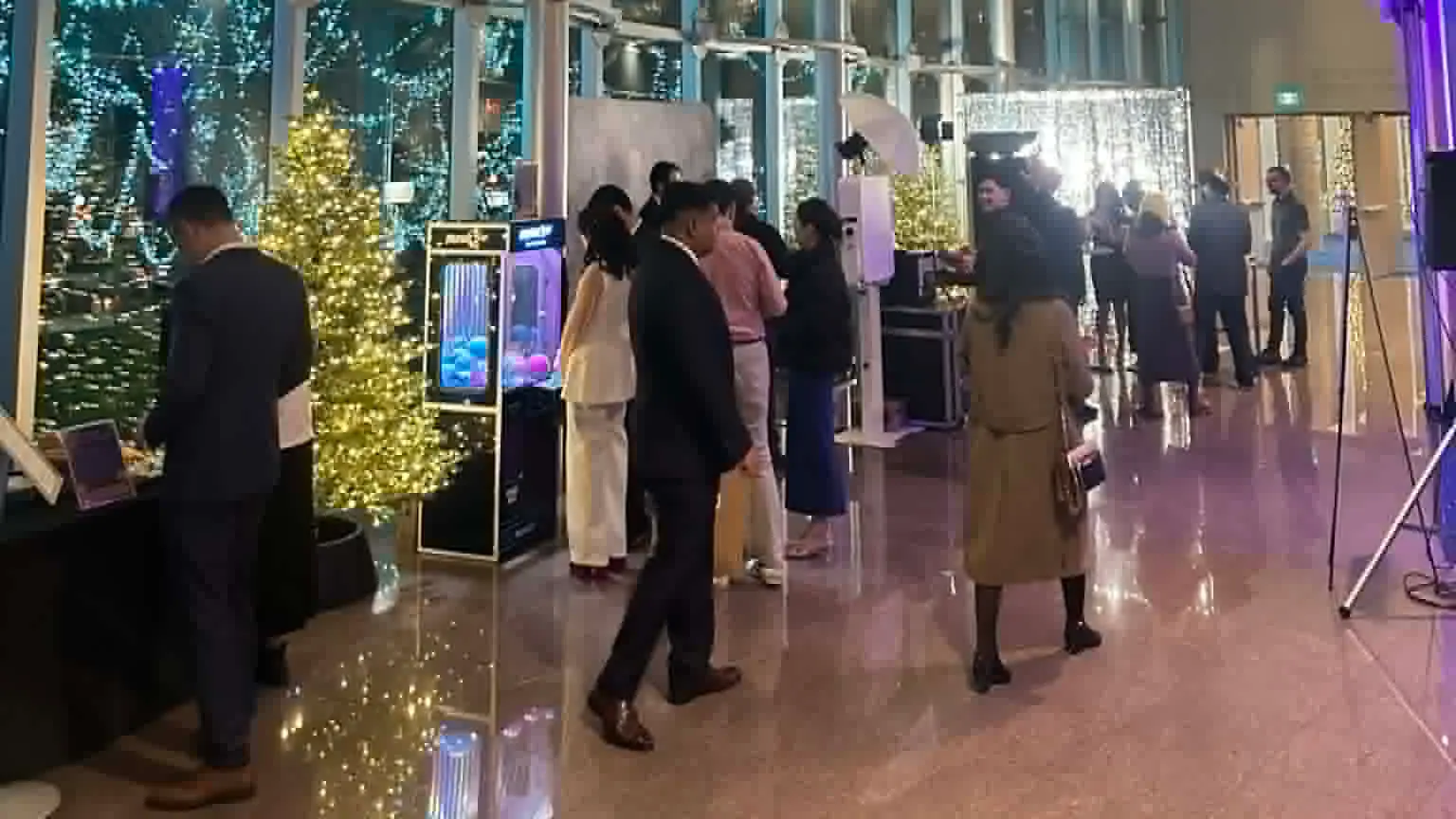 Guests playing a claw machine and using a photo booth at a corporate holiday event