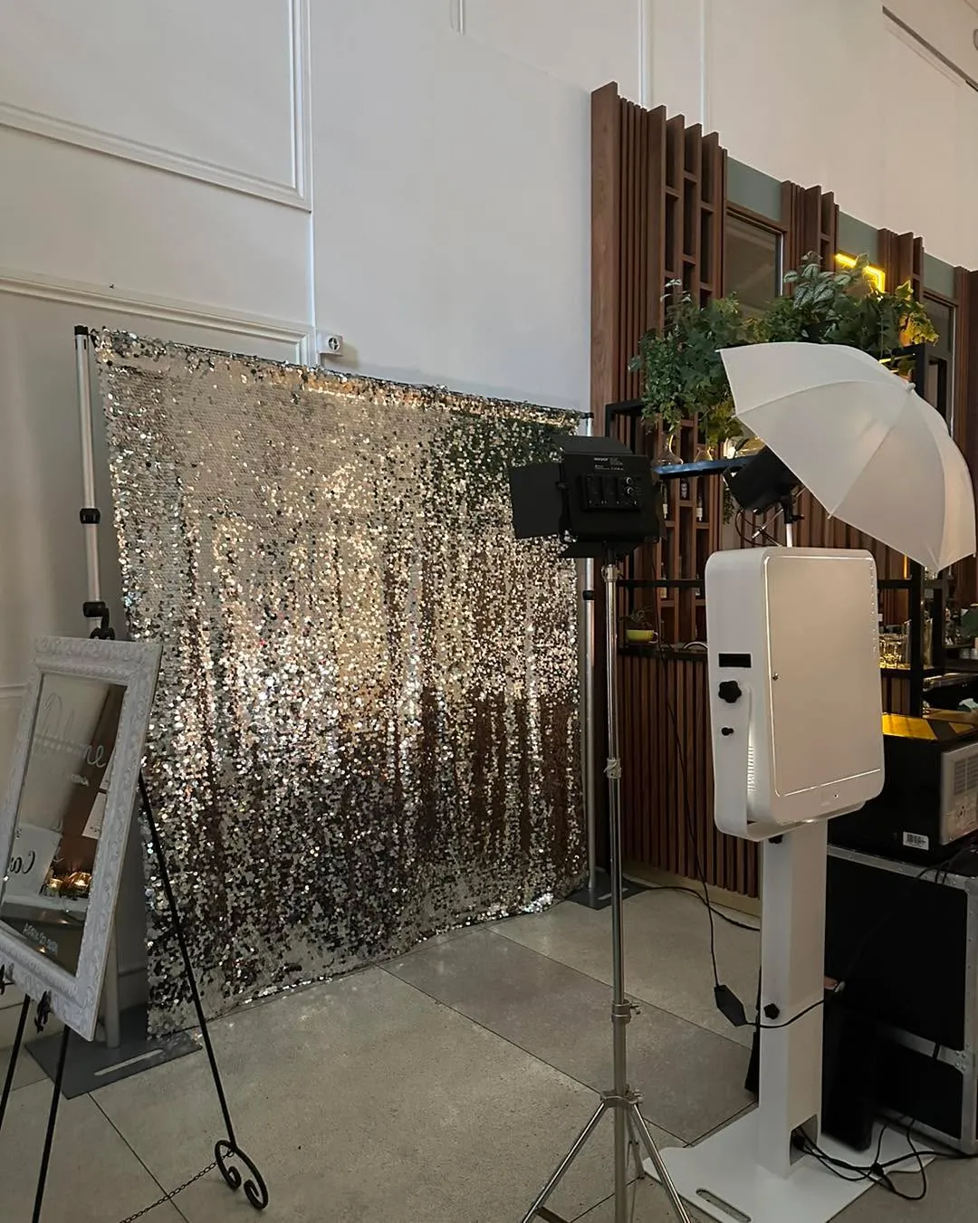 White DSLR open air photo booth setup with a silver sequin backdrop and studio lighting at an elegant venue